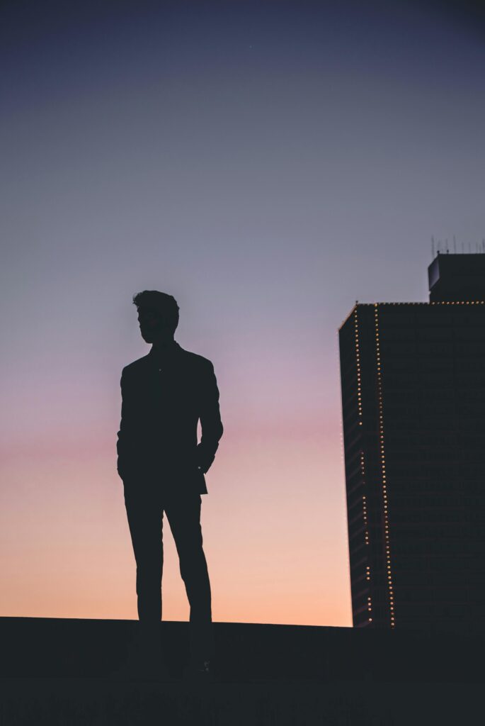 Silhouette of a man standing against a colorful Fort Worth sunset skyline, capturing urban tranquility.