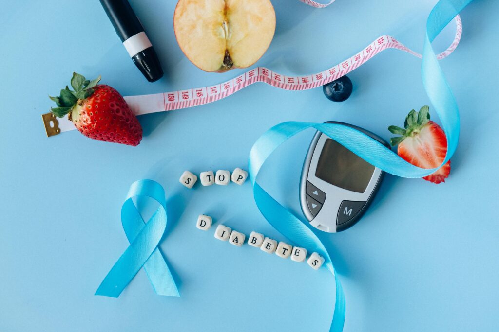 Creative diabetes awareness with fruits, glucometer, and ribbon on blue background.